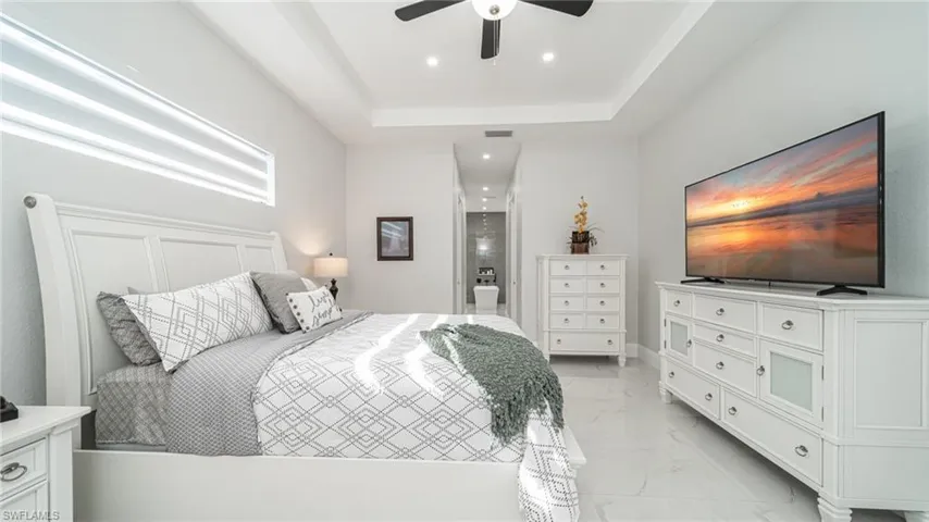 Tiled bedroom featuring a raised ceiling and ceiling fan
