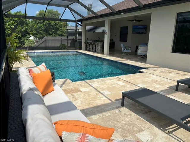View of swimming pool featuring a patio, glass enclosure, outdoor lounge area, and ceiling fan