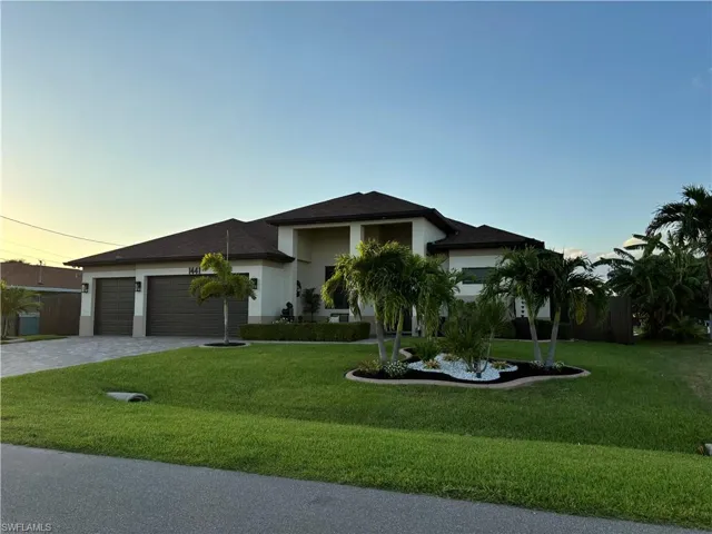 View of front facade with a garage and a lawn