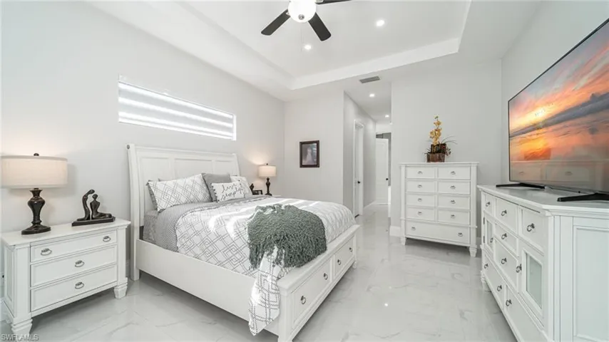 Tiled bedroom with a tray ceiling and ceiling fan