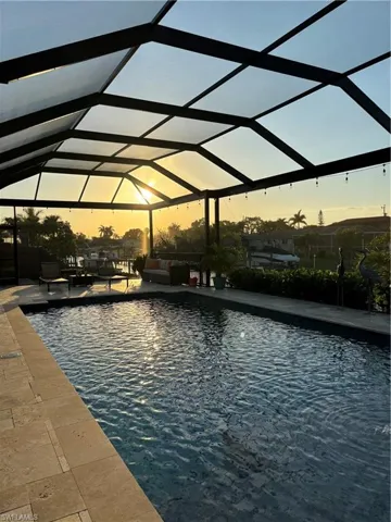 Pool at dusk featuring a patio area and a lanai