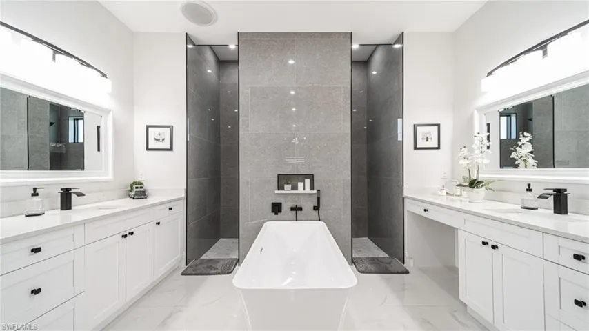 Bathroom featuring a bath to relax in, vanity with extensive cabinet space, and tile floors