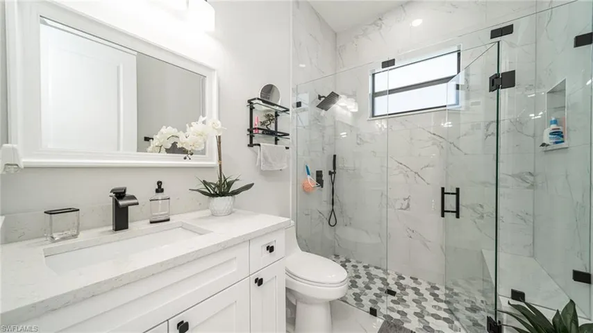 Bathroom with tile floors, a shower with shower door, toilet, and vanity