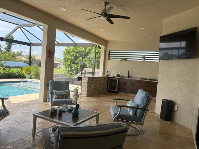 View of patio with wine cooler, a lanai, sink, and ceiling fan