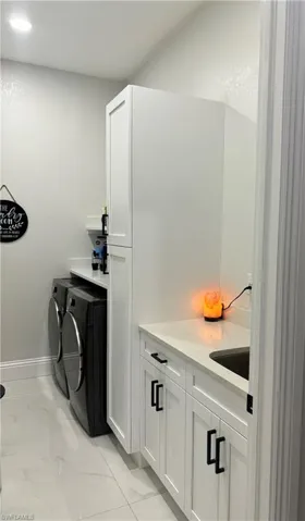 Laundry area featuring cabinets, light tile flooring, and washing machine and dryer