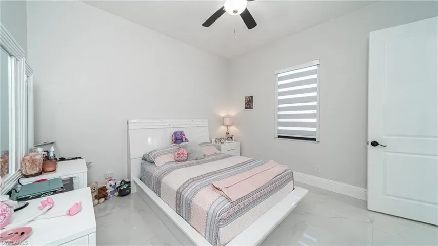 Bedroom with ceiling fan, light tile floors, and multiple windows