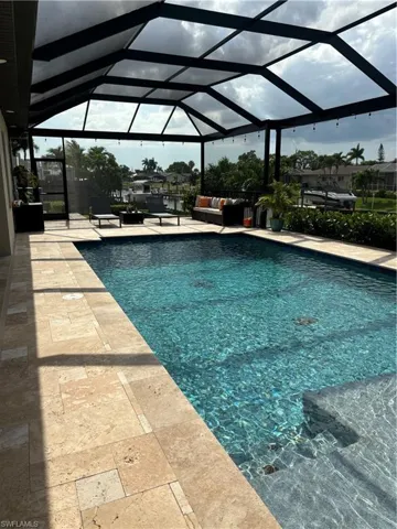View of pool featuring glass enclosure and a patio