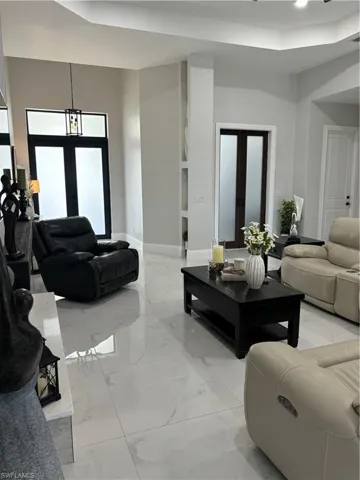 Tiled living room featuring a towering ceiling and french doors
