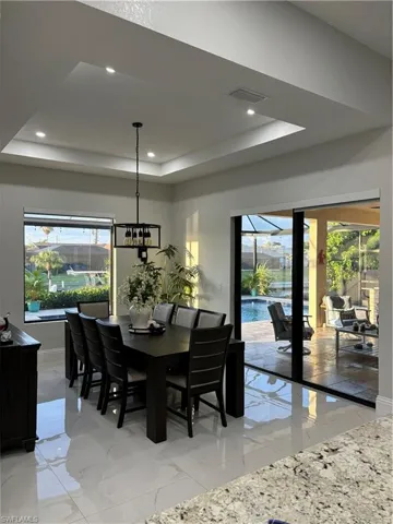 Dining room with a tray ceiling, a healthy amount of sunlight, and an inviting chandelier