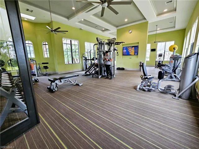 Exercise room featuring a ceiling fan, high coffered ceiling, and recessed lighting