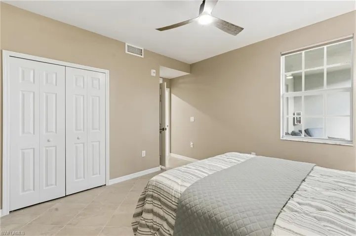 Bedroom featuring ceiling fan, light tile patterned floors, and a closet