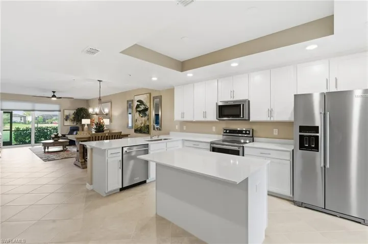 Kitchen with stainless steel appliances, decorative light fixtures, white cabinetry, a peninsula, and light tile patterned floors