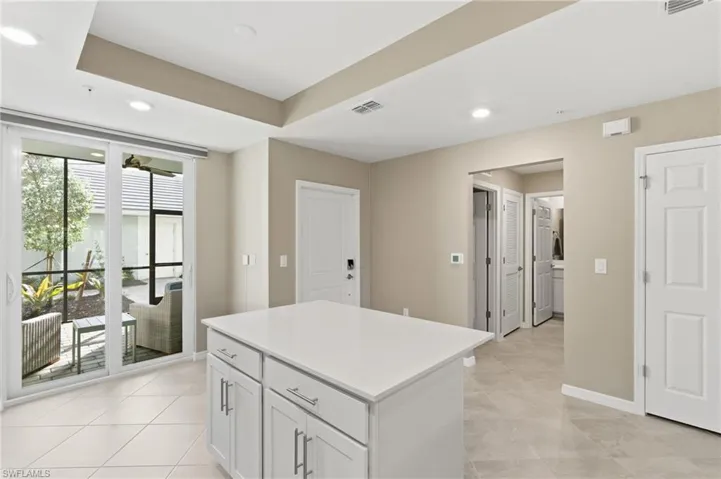 Kitchen featuring recessed lighting, white cabinetry, a center island, light tile patterned floors, and a raised ceiling