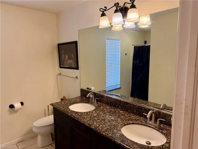 Full bath featuring double vanity, curtained shower, and light tile patterned flooring
