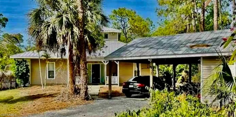 View of front facade featuring a carport, a porch, and driveway
