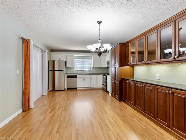 Dining area and Kitchen with sink, an inviting chandelier, decorative light fixtures, stainless steel appliances, and light hardwood / wood-style floors