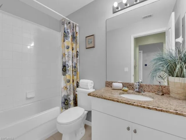 Full bathroom with vanity, shower / tub combo with curtain, and tile patterned floors