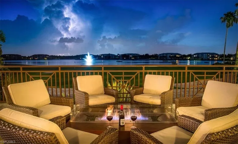 Clubhouse view of patio featuring a water view and an outdoor living space with a fire pit