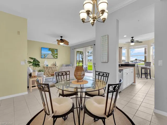 Dining area with a ceiling fan, light tile patterned flooring, ornamental molding, and a chandelier