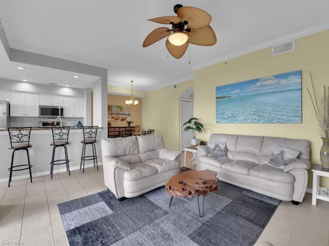 Living room featuring light tile patterned floors, a ceiling fan, a chandelier, crown molding, and recessed lighting
