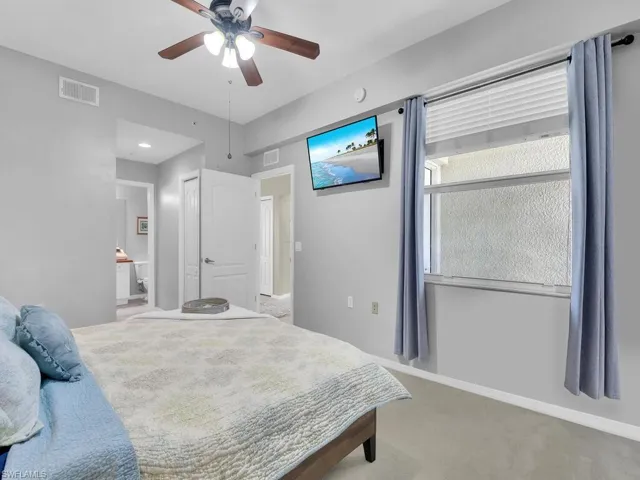 Carpeted bedroom with ensuite bath and a ceiling fan