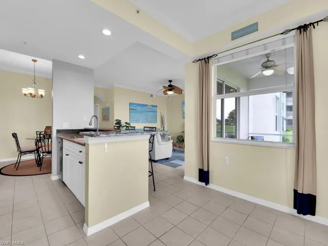 Kitchen featuring a ceiling fan, dark stone counters, light tile patterned flooring, a breakfast bar area, and recessed lighting