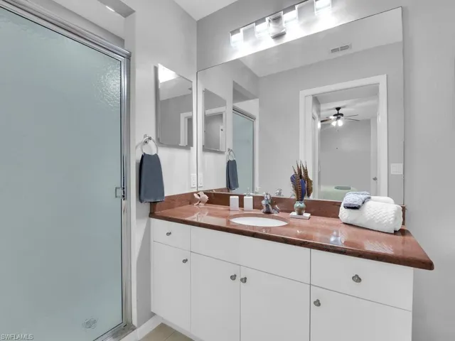 Bathroom featuring vanity, a shower stall, and ceiling fan