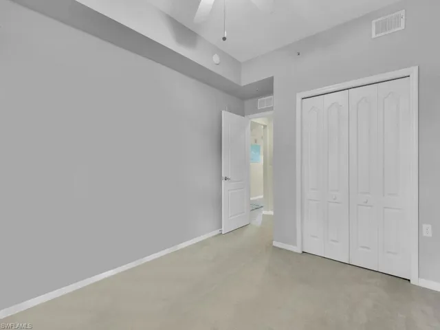 Unfurnished bedroom featuring light colored carpet, a closet, and a ceiling fan