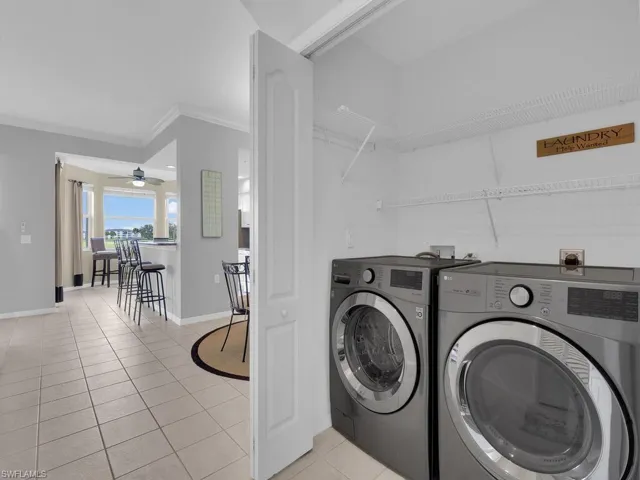 Washroom featuring separate washer and dryer, ornamental molding, light tile patterned floors, and ceiling fan