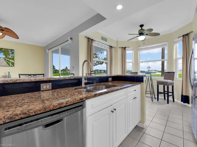 Kitchen featuring dishwasher, a ceiling fan, ornamental molding, light tile patterned floors, and white cabinetry