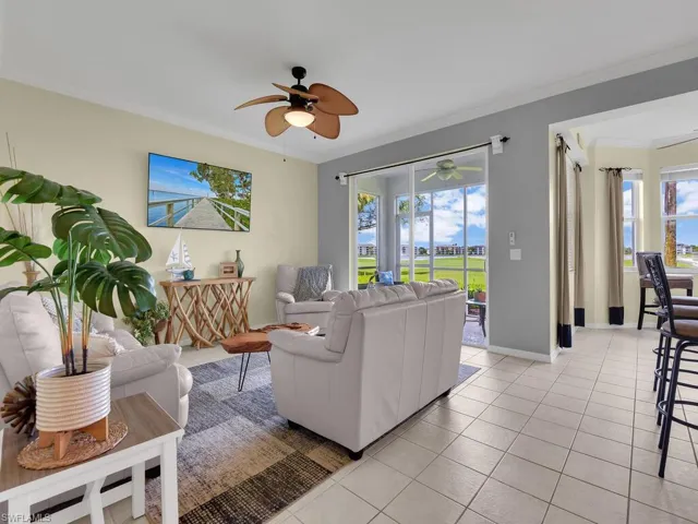 Living area with ceiling fan, crown molding, plenty of natural light, and light tile patterned floors