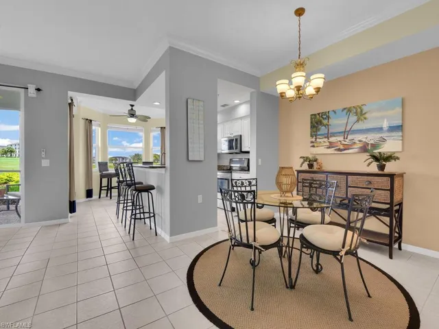Dining room featuring ornamental molding, a chandelier, light tile patterned floors, and a ceiling fan