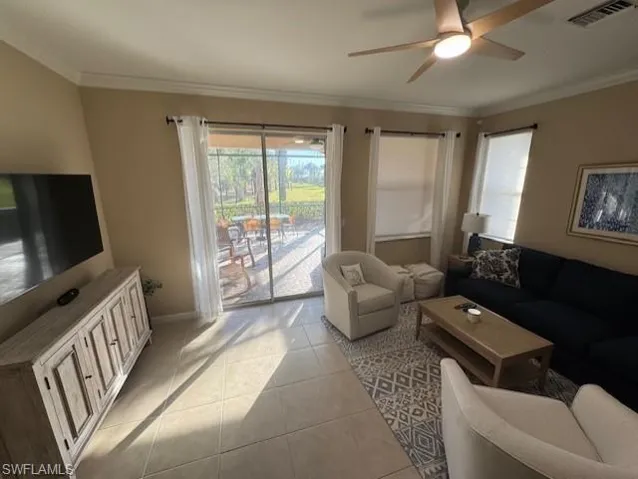 Living room with light tile patterned flooring, crown molding, and a ceiling fan