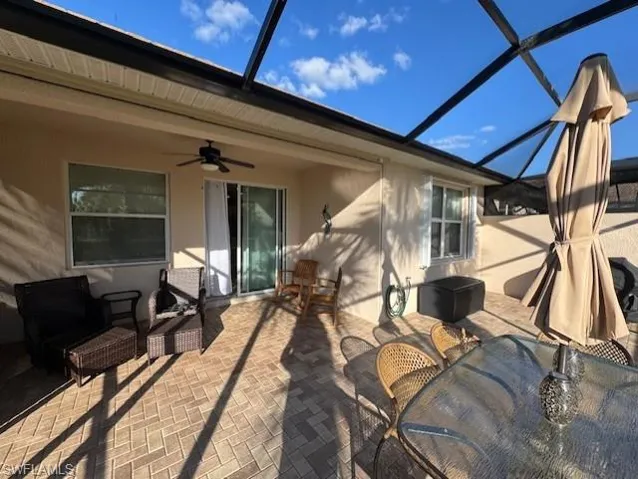 View of patio featuring a sunroom, a ceiling fan, glass enclosure, and outdoor dining space