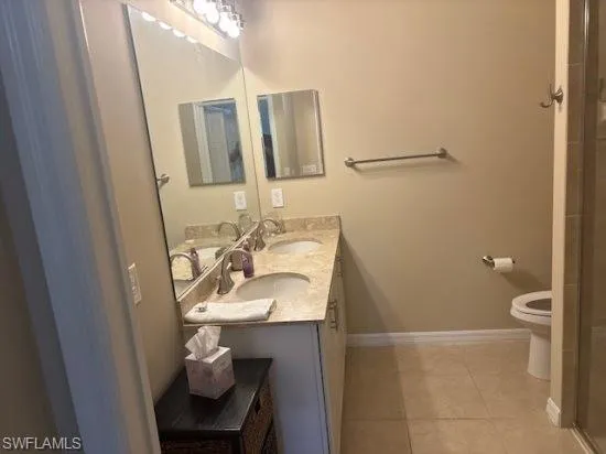 Full bathroom featuring double vanity, light tile patterned floors, and an enclosed shower