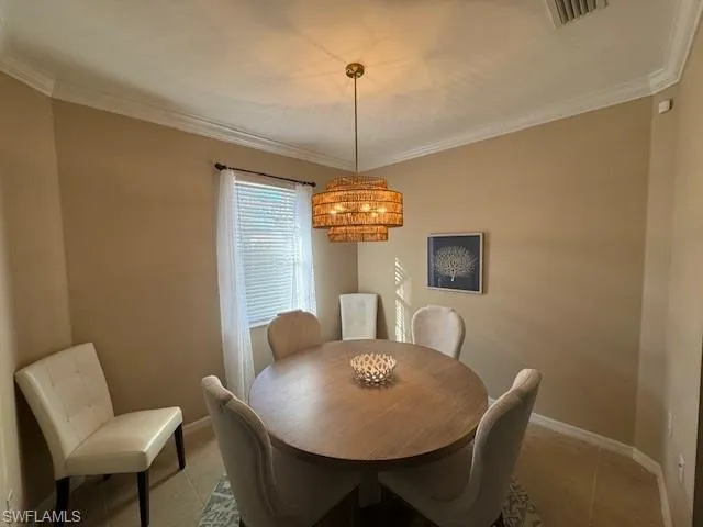 Tiled dining area with baseboards and crown molding