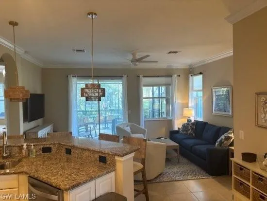 Kitchen with open floor plan, crown molding, white cabinetry, dark stone counters, and ceiling fan