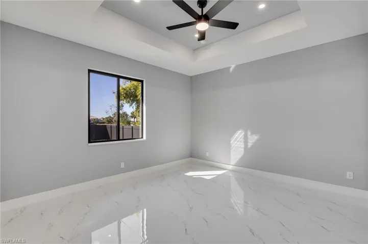 Master bedroom with recessed lighting, a ceiling fan, marble finish flooring, and tray ceiling
