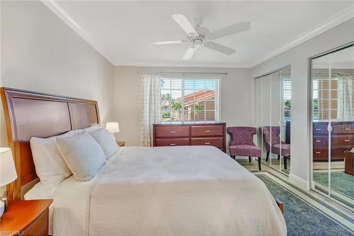 Bedroom with two closets, crown molding, ceiling fan, and wood finished floors