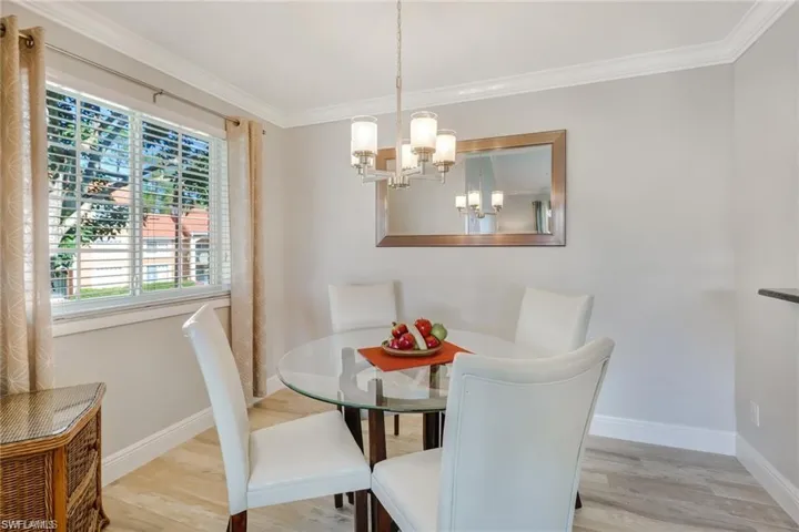 Dining space featuring wood finished floors, ornamental molding, and hanging lights