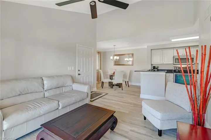 Living area featuring ornamental molding, light wood-type flooring, a ceiling fan, vaulted ceiling, and a chandelier