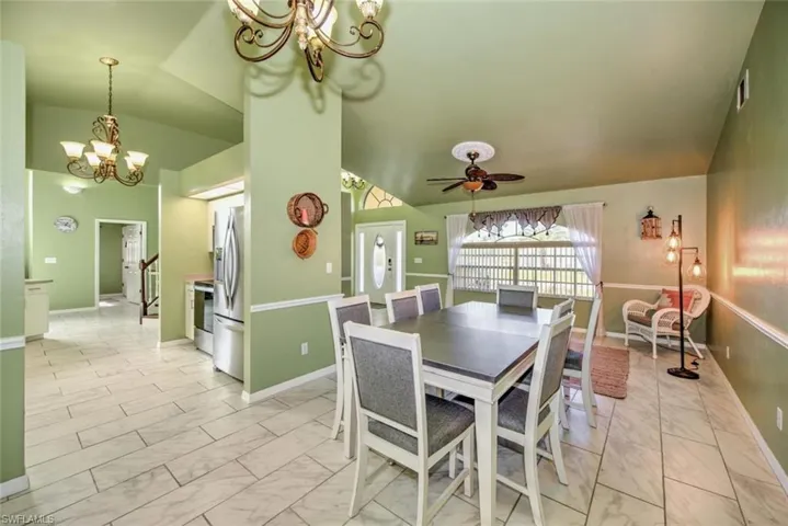 Dining room with a chandelier, light marble finish floors, a ceiling fan, and vaulted ceiling