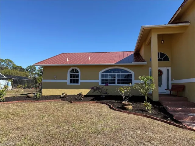 View of front of home featuring a metal roof, stucco siding, and a front lawn