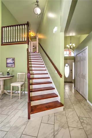 Stairway with a chandelier, a high ceiling, and marble finish flooring