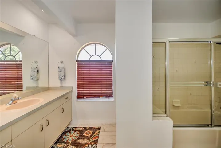 Bathroom featuring bath / shower combo with glass door and vanity