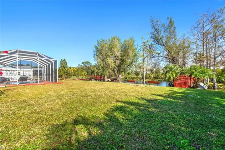 View of grassy yard with a lanai, a water view, an outdoor pool, and a sunroom