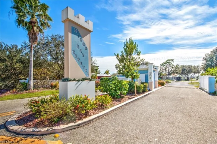 View of asphalt road with a gate, curbs, and a gated entry