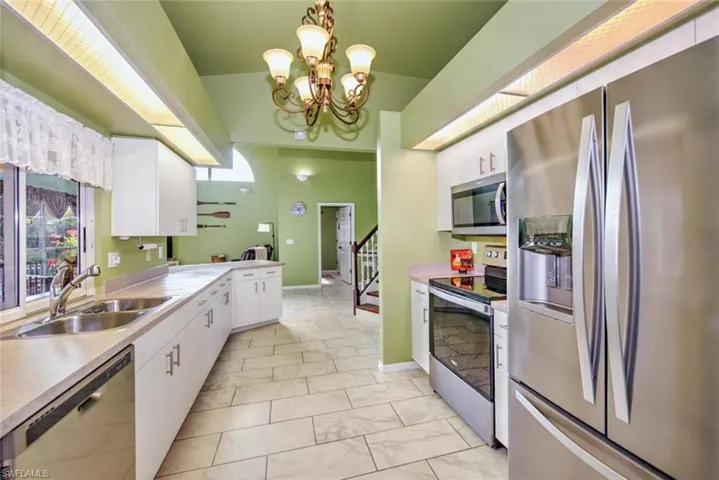 Kitchen with appliances with stainless steel finishes, pendant lighting, plenty of natural light, and white cabinets