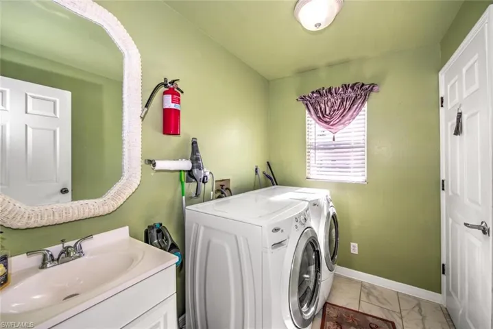 Laundry room with washing machine and clothes dryer and light marble finish flooring