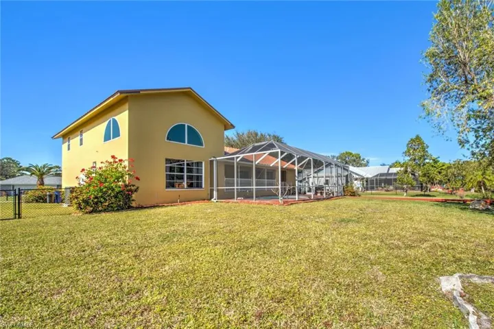 Back of property with glass enclosure, stucco siding, a sunroom, a fenced backyard, and a gate